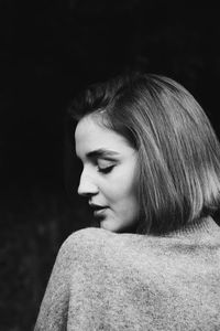 Close-up of young woman against black background