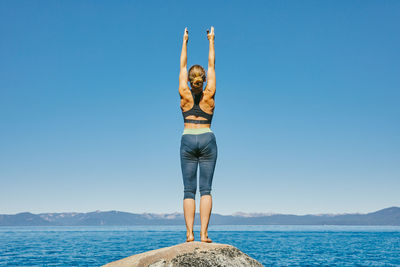 Young woman practicing yoga on lake tahoe in northern california.