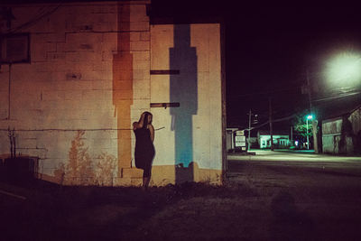 Side view of woman standing on street in city at night