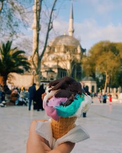 Cropped hand of person holding ice cream cone in city