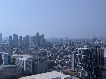 Aerial view of buildings in city against clear sky