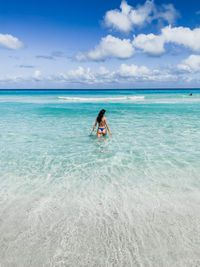 Woman standing in sea against sky