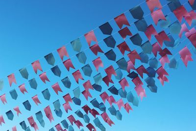 Low angle view of flags against clear blue sky