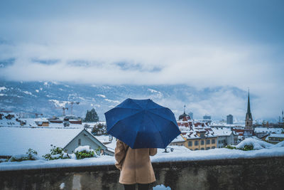 Rear view of woman in city against sky