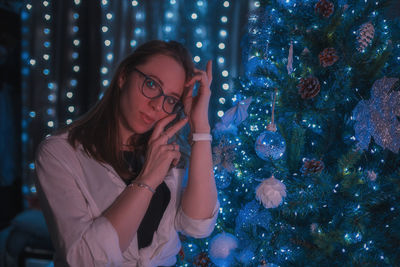 Portrait of young woman against christmas tree