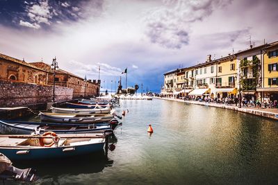 Boats moored in river against sky in city