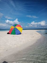 Multi colored umbrella on beach against sky