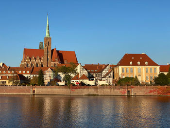 View of buildings against blue sky behind a river 