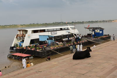 Fishing boats moored at harbor against sky