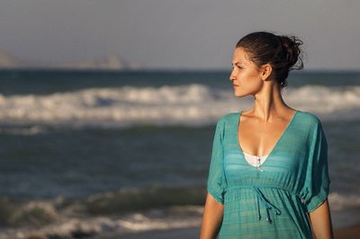Close-up of young woman standing at beach against sky