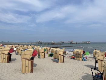 Hooded chairs on beach against sky