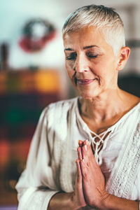 Mature woman meditating with closed eyes at spa