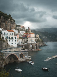 Buildings by sea against sky