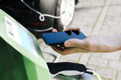 Hand of man scanning through smart phone at car charging kiosk