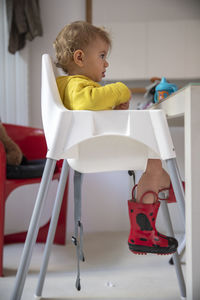 Boy looking away while sitting on chair at home