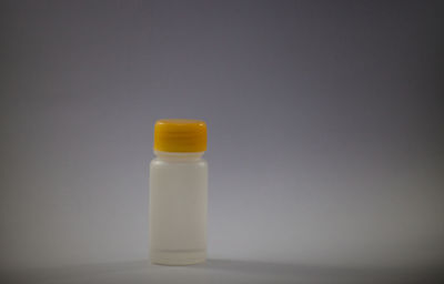 Close-up of green bottle on table against white background