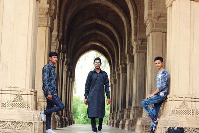 Full length of young men standing against historical building