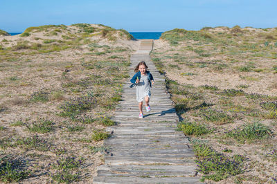 Girl running on footpath amidst grass