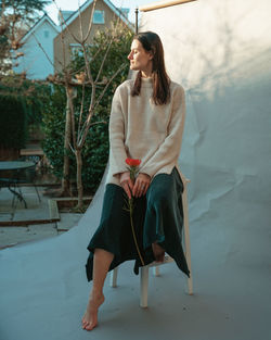 Portrait of young woman standing against wall