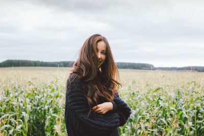 Young woman standing on field against sky