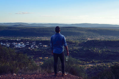 Rear view of man standing on landscape against sky