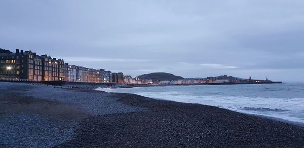 Scenic view of sea by city buildings against sky