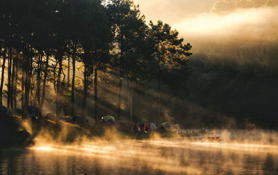 Idyllic lake by tents during foggy weather