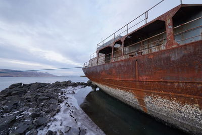 Abandoned boat on sea shore during winter