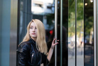 Young woman standing by door of store