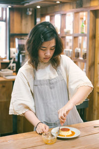 Mid adult woman holding food while standing on table