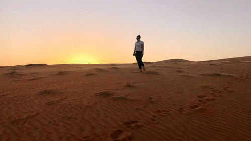Full length rear view of man standing on sand dune