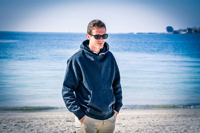 Young man wearing sunglasses standing on beach