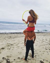 Full length of man and woman on beach against sky