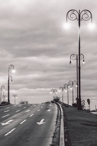 Street light on road against cloudy sky