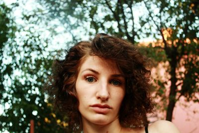 Close-up portrait of young woman with short curly hair at yard