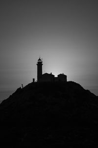 Silhouette building on mountain against sky during sunset