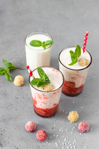 Layered strawberry and raspberry smoothie or milkshake with mint, raspberry and coconut flakes. 