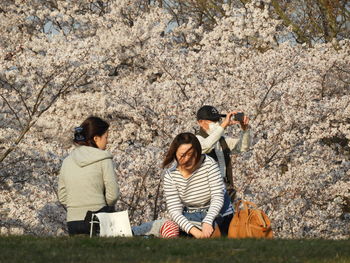 Young woman photographing while sitting on grass