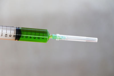 Close-up of syringe against gray wall