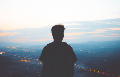 Rear view of man standing on mountain against sky