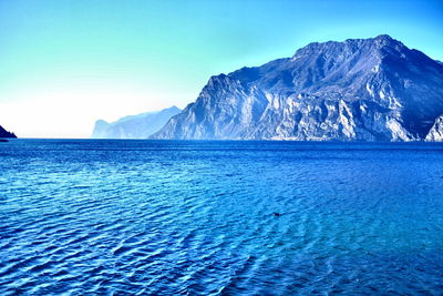 Scenic view of sea and mountains against clear blue sky