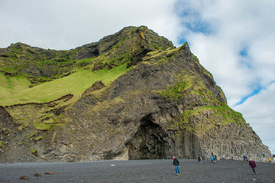 People on rock formations against sky