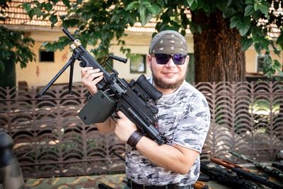 Man holding gun against tree