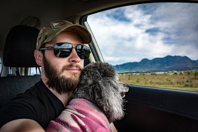 Portrait of young man with dog sitting in car