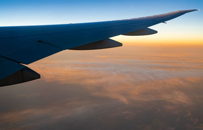 Wing of plane over white clouds. airplane flying on sunrise sky. scenic view from airplane window. 