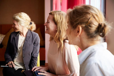 Smiling female entrepreneurs sitting in office seminar at workplace