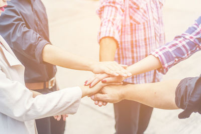 Midsection of people stacking hands while showing unity