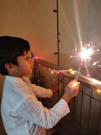 Side view of boy with umbrella standing at night