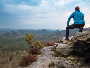 Rear view of man standing on mountain against sky