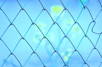 Full frame shot of chainlink fence against blue sky